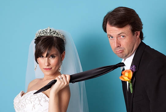 bride holds husband by the tie